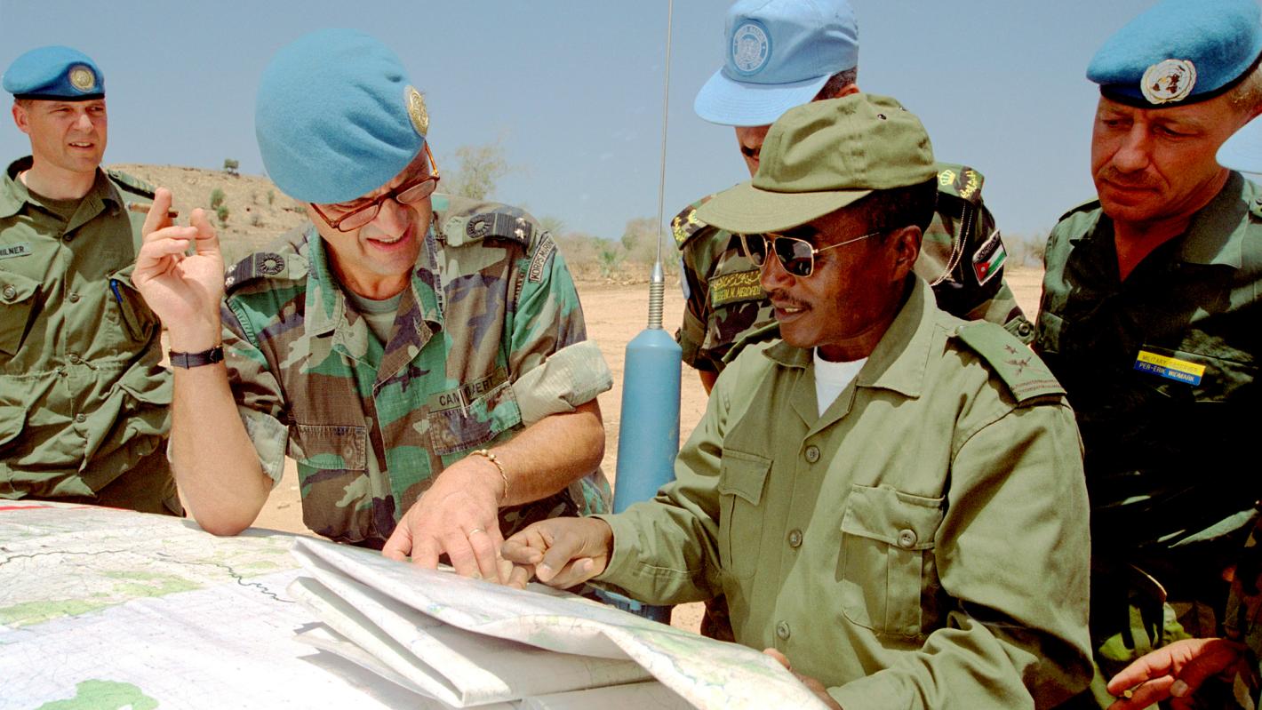 UN Peacekeepers looking at a map that is placed on the front of a car.