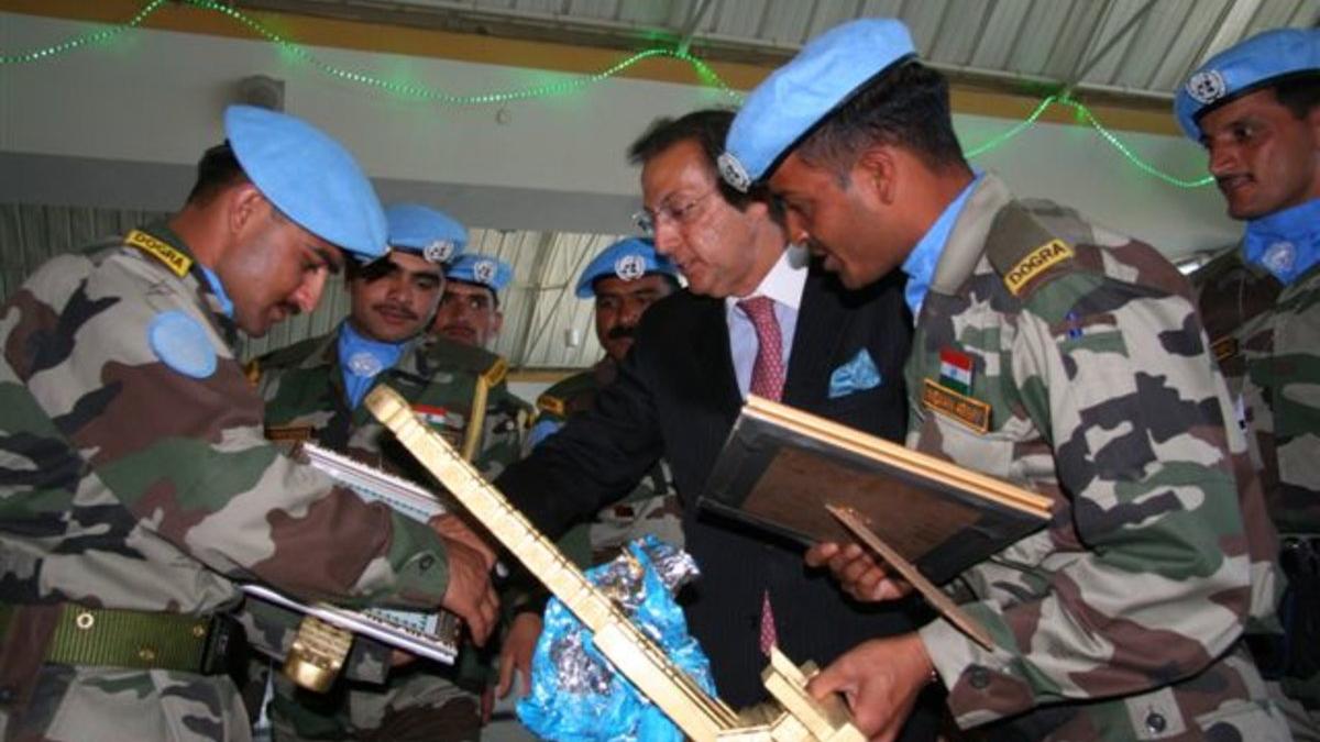 Peacekeepers in blue berrets shake hands at a farewell ceremony