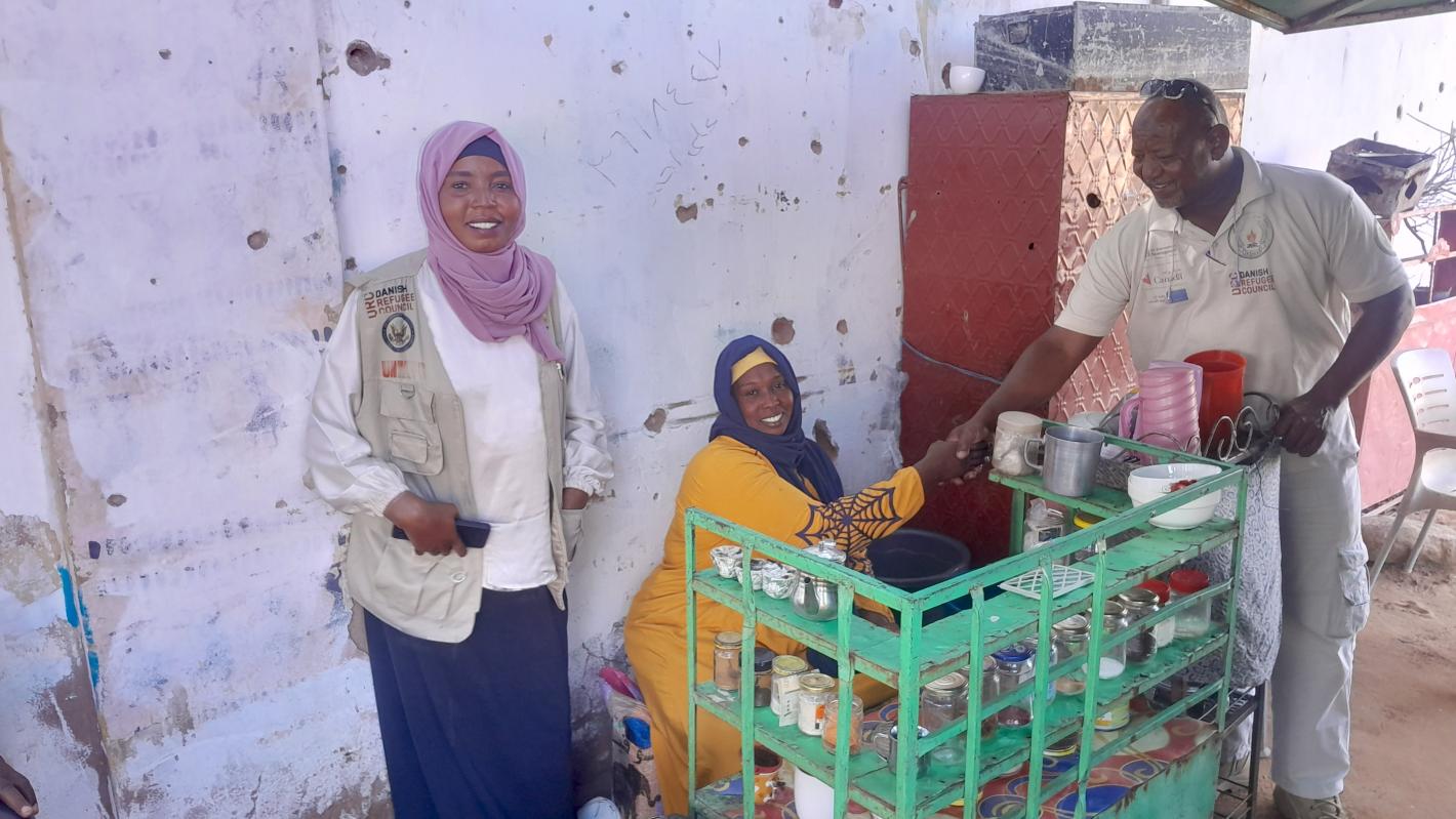 a woman is standing beside a woman shaking hand with a man