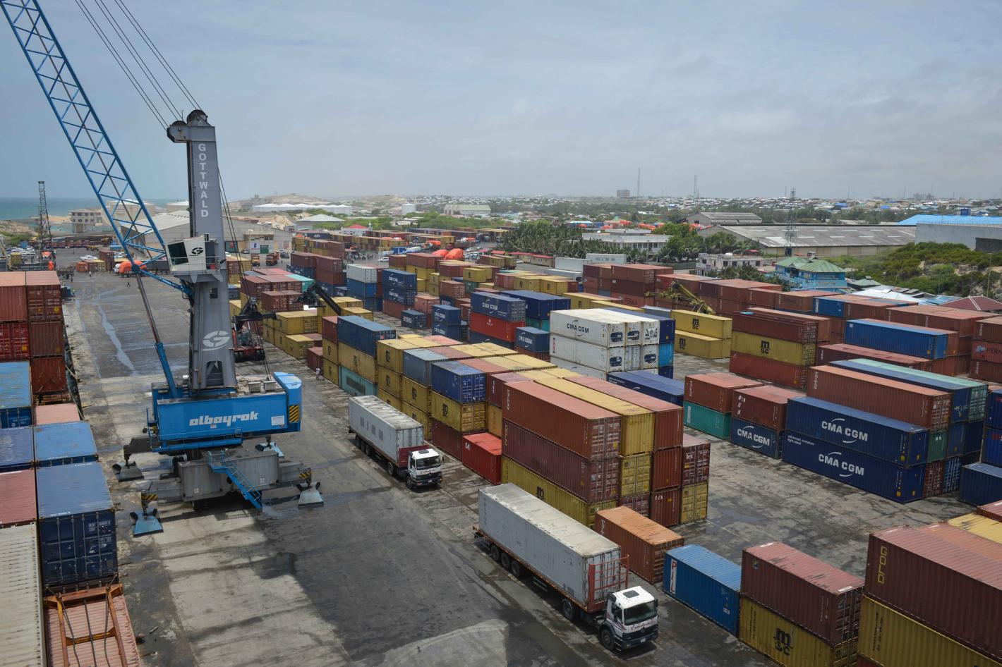 An aerial view of shipping containers, trucks and a large crane