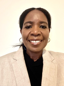A woman stands in front of a white background, smiling for the camera